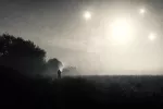 Figura solitaria en un campo brumoso bajo varias luces en el cielo, en una ilustración de estilo antiguo.